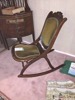 Side view of antique mahogany folding rocking nursing chair with upholstered seat and back
