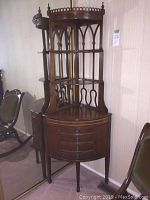 Full front view of the corner cabinet showing curved front, shelves, drawers, gallery top