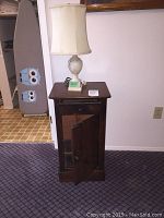 Full view showing the antique cabinet with open cupboard door and soapstone lamp on top.