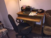 Photo of wooden desk with pullout keyboard tray, Asus Eee PC laptop on top, black office chair in front, and assorted office items on the desktop.