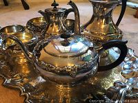 Photo showing the full tea set with teapot, coffee pot, hot water pot, sugar bowls, creamers and the serving tray beneath them