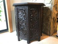Front view showing carved panels with maple leaf motifs and folding legs.