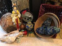 Photo showing assorted Oriental decorative items including figurine, urn, embroidered panda, slippers, baskets, and fan.