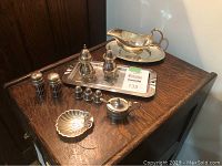 Photo of the full assortment of silver plated dinnerware on a wooden surface showing serving tray and various condiment containers