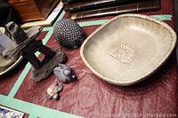 Lot showing earthenware bowl, hand-cast stone Inukshuk, and small animal figures on red surface