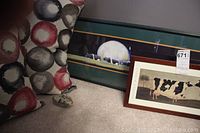 View showing two cushions with circular patterns and a framed print on the floor