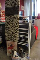 Full view of the ironing board with leopard print cover, drying rack laid folded, boxed T Fal iron and Small Wonder iron box visible.