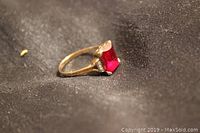Side angle view of the ring showing the stone and band detail on dark fabric background.