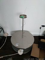 Full view of large round ceiling light fixture with central mounting rod and visible electrical cords.