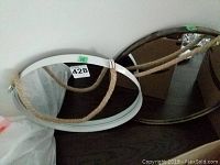 Two round mirrors placed side by side, one with a white frame and the other with a dark metallic frame, both having rope hangers attached.