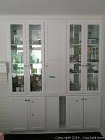 Full view of built-in wooden cabinet with double beveled glass doors left and right and solid door in center, and lower solid wooden doors.