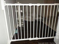 White metal gate installed in an opening, showing the full gate and bars.