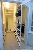 Wide view of hallway closet space with white modular units including shelves, drawers, and hanging rods.