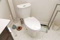 White two-piece Toto toilet installed next to plunger and exposed waste flange