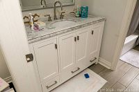 Front view of installed white bathroom vanity with marble countertop and undermount sink