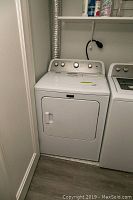 Full view of the white Maytag dryer installed next to a washing machine with vent hose connected.