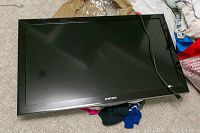 Front angled view of Samsung TV panel with power cable lying on floor
