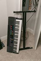 Photo of the Casio CTK-480 keyboard leaning on the black metal X-style stand inside a room on carpet floor.