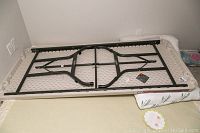 Full view of the folding table turned upside-down showing plastic tabletop and black metal folding legs.