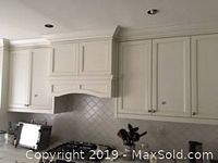 Front view of upper cabinets with crown molding above stove area