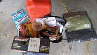 Overview of lot showing various items including battery charger, cleaning cloths, emergency blanket and kit, funnel, and polisher box.