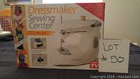 Front view of Dressmaker Sewing Center box showing machine image and text describing 100-piece accessory kit