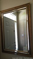 Full view of the rectangular wall mirror hanging on a wall, showing the door and window reflection.