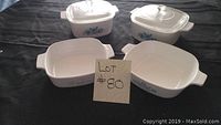 Full set of four CorningWare Blue Flowers casserole dishes displayed on a black surface, two dishes with covers and two open, with lot number display