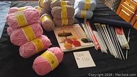 Overview of yarn skeins in various colors, knitting instruction booklet and assorted needles.