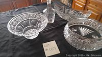 Photo shows three large crystal bowls and one tall crystal decanter with stopper arranged on a black cloth.