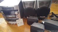 Full view of JVC stereo unit with three speakers surrounding it on floor.