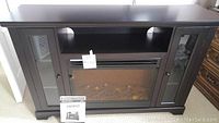 Full front view of the MasterFlame Kingwood electric fireplace entertainment unit showing wood finish cabinet, glass doors on sides, and simulated fire in center.