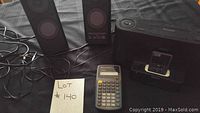 Overall lot with Sony iPod dock, two speakers, and TI-30Xa calculator on a black fabric surface.
