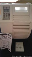 White Honeywell portable air purifier standing next to its owner's guide and a small paper with lot number.
