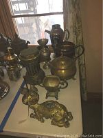 Nine heavily tarnished pieces including jugs, camel candleholder, pepper and salt rack, ceramic column, sugar bowl.