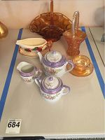 Seven-piece lot laid out on table showing all main items in lot including tea set, carnival glass, basket, and gravy boat