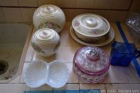 Overview of all items showing ceramic canisters, covered dish, milk glass divided candy dish, Kings Crown candy dish, and blue Hazel Atlas creamer