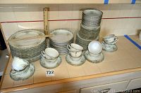 Full view of the Mikado China set showing stacks of plates in various sizes, cups, saucers, and bowls on counter.