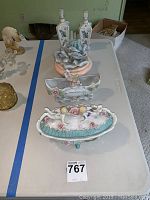 Top view of several vintage glass and porcelain decorative dishes and containers arranged on a table.