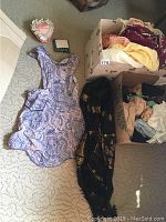 Overview of paisley pattern apron, heart-shaped scent pillow, boxed garments including scarves and lace items