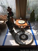 Full view of lot showing the ceramic figurine, pottery bottle, wall clock frame with milk glass face, and Egyptian decorative plate.