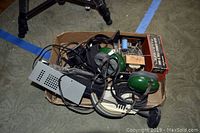 Box containing wired green headphones, various power supplies, and miscellaneous electronic components