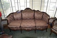 Front view of vintage Victorian formal sofa with carved wood and floral damask silk upholstery