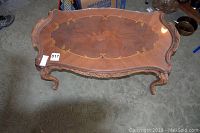 Top view showing ornate wood inlay pattern with glass protective top on vintage coffee table.
