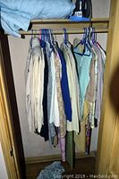 Closet rack holding assorted vintage sweaters and clothing items on hangers.
