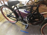 Photo showing the side view of the black Dyno Glide Deluxe bicycle with 'Glide deluxe' script on the frame and the helmet hanging from the handlebars.