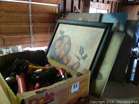 Box of assorted flashlights next to canvas paintings leaning on a wall