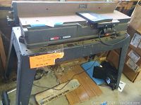 Full view of Craftsman 5 inch jointer showing the full length and metal stand with a bright orange information paper attached to the front.