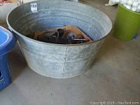 Large vintage metal wash tub on the floor, showing the overall size and condition.