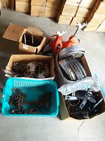 Overview of boxed and basketed items including Chevy hubcaps, miscellaneous hubcaps, chains, and two orange car jacks.
